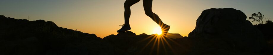 Frau beim Joggen in den Bergen und Sonnenuntergang